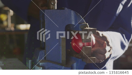Coverall-clad technician clamping baseball in blue metal vise at shop workbench, with blurred tools Coverall-clad technician clamping baseball in blue metal vise at shop workbench, with blurred tools 135816645