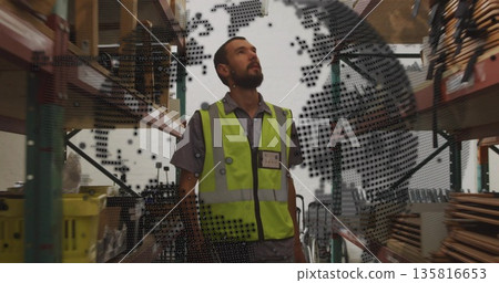Gazing worker wearing yellow safety vest in warehouse aisle flanked by racks, with globe overlay Gazing worker wearing yellow safety vest in warehouse aisle flanked by racks, with globe overlay 135816653