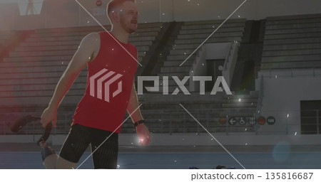 Stretching athlete in red sleeveless top bending leg on blue stadium track, with fitness tracker Stretching athlete in red sleeveless top bending leg on blue stadium track, with fitness tracker 135816687
