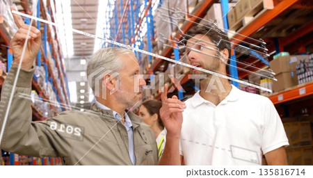 Holding planning board, two men pointing with marker at markings in warehouse aisle, with racks Holding planning board, two men pointing with marker at markings in warehouse aisle, with racks 135816714