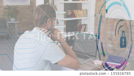 Studying IT professional resting chin at home office, with laptop coffee mug and security graphics 135816785
