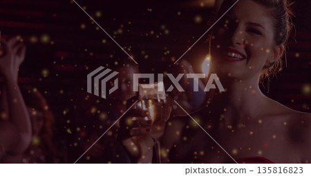 Smiling attendee in red dress holding champagne glass at lounge amid golden sparkles, copy space Smiling attendee in red dress holding champagne glass at lounge amid golden sparkles, copy space 135816823