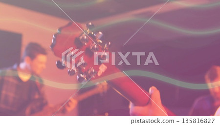 Framing musician holding headstock with chrome tuning pegs in rehearsal, stage lights creating haze 135816827