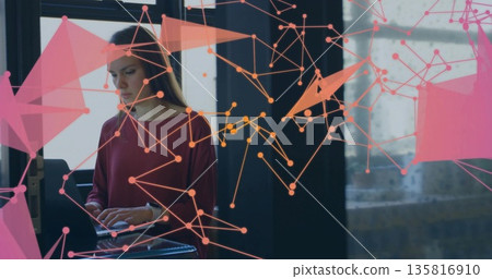 Working woman typing on laptop at glass-topped table in modern loft, with digital network overlay Working woman typing on laptop at glass-topped table in modern loft, with digital network overlay 135816910