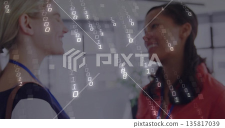 Chatting two colleagues wearing blouses and ID badges in modern office, with binary overlay Chatting two colleagues wearing blouses and ID badges in modern office, with binary overlay 135817039