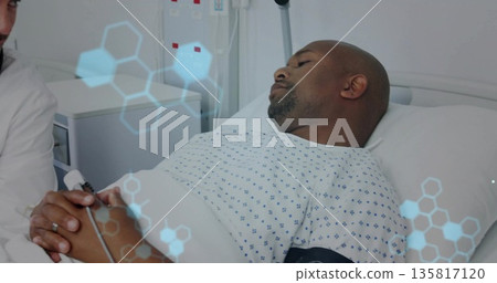 White coat doctor holding gown-clad patient hands on hospital bed, with IV pole and graphics White coat doctor holding gown-clad patient hands on hospital bed, with IV pole and graphics 135817120