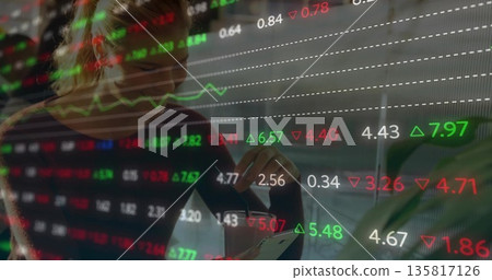 Sitting woman monitoring smartphone at desk with potted plant and stock market overlays, copy space 135817126