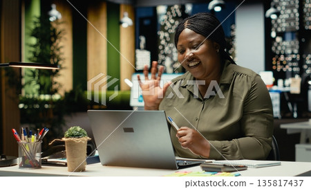 African american CEO joins online meeting at night in corporate office, eye contact with the webcam. Manager focused on communication, participating in a collaborative dialogue. Camera B. African american CEO joins online meeting at night in corporate office, eye contact with the webcam. Manager focused on communication, participating in a collaborative dialogue. Camera B. 135817437