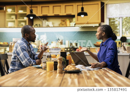 African American couple arguing over bills and debt sitting at the table, frustrated people with receipts and calculator. Financial conflict shows stress, money problems and household tension. African American couple arguing over bills and debt sitting at the table, frustrated people with receipts and calculator. Financial conflict shows stress, money problems and household tension. 135817491