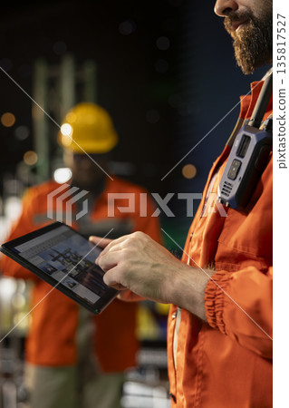 Close up of offshore platform engineer checking equipment status indicators on tablet system dashboard. Worker verifying hydraulic pressure levels on device digital monitoring panel app 135817527