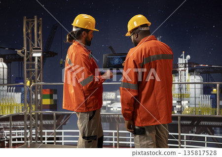 Offshore platform engineers utilizing artificial intelligence software to optimize drilling precision. Drilling rig crew monitoring equipment performance using automated AI tracking system on laptop Offshore platform engineers utilizing artificial intelligence software to optimize drilling precision. Drilling rig crew monitoring equipment performance using automated AI tracking system on laptop 135817528