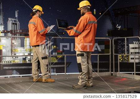 Offshore platform professional using neural network AI models to forecast gear maintenance needs. African american man on drilling rig analyzes machine learning data to prevent mechanical failures Offshore platform professional using neural network AI models to forecast gear maintenance needs. African american man on drilling rig analyzes machine learning data to prevent mechanical failures 135817529