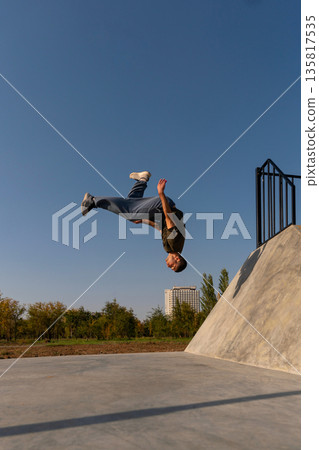 Man completing backflip from concrete ramp in parkour run 135817535