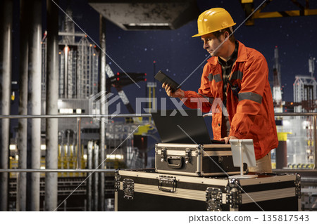 Offshore platform worker ensuring oil extraction activity on laptop under northern lights, conducting natural gas operations for oil production through advanced engineering and tools. Offshore platform worker ensuring oil extraction activity on laptop under northern lights, conducting natural gas operations for oil production through advanced engineering and tools. 135817543