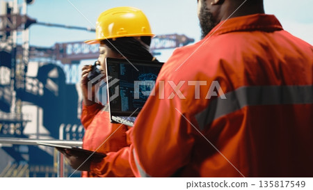 Offshore platform crew using artificial intelligence program on laptop to optimize drilling operations. African american coworkers analyzing geology data using AI tech on notebook 135817549