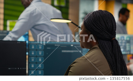 Programmer solving tasks with AI LLM chatbot answering prompts using predictive technology. Startup company worker using computer to interact with large language model program, camera B 135817556