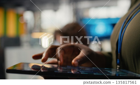 Close up of tablet used by programmer in office to accelerate complex artificial intelligence calculations. IT employee using touchscreen device to train deep learning datasets systems, camera A 135817561