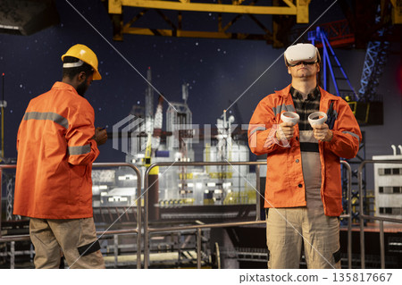 Male offshore oil industry employee working with VR headset to visualize fuel extraction process, improving operational monitoring and risk management. Oil production efficiency. Male offshore oil industry employee working with VR headset to visualize fuel extraction process, improving operational monitoring and risk management. Oil production efficiency. 135817667