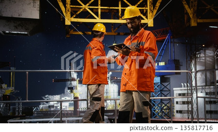 Offshore worker use walkie talkie to manage drilling rig operations at sea, ensuring correct and efficient petroleum extraction. Fuel production in the oil and gas industry. Offshore worker use walkie talkie to manage drilling rig operations at sea, ensuring correct and efficient petroleum extraction. Fuel production in the oil and gas industry. 135817716