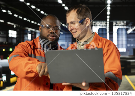 Engineers team coordinates strong labor in industry plant with gadgets, demonstrating engineering development and the heavy production workflow essential to modern manufacture. 135817824