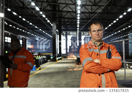 Portrait of technician oversees metal fabrication during production in workshop, highlighting heavy labor. Automation development and job responsibilities within manufacturing facility. Portrait of technician oversees metal fabrication during production in workshop, highlighting heavy labor. Automation development and job responsibilities within manufacturing facility. 135817835