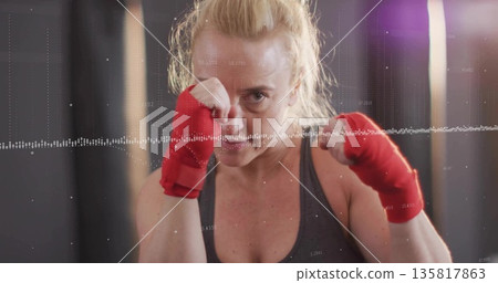 woman with red wraps wearing grey tank punching toward camera in gym, with waveform overlay woman with red wraps wearing grey tank punching toward camera in gym, with waveform overlay 135817863
