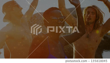 Celebrating friends raising arms on rocky shore at sunset, wearing sunglasses and pendant necklace Celebrating friends raising arms on rocky shore at sunset, wearing sunglasses and pendant necklace 135818045