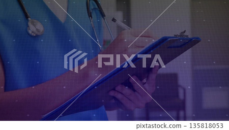 Writing male doctor in blue scrubs stethoscope taking notes in clinic corridor, with clipboard, pen 135818053