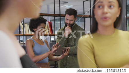 Presenting tablet, woman in blue top explaining data to bearded coworker in open-plan office Presenting tablet, woman in blue top explaining data to bearded coworker in open-plan office 135818115
