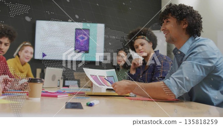 Four colleagues reviewing mock-ups and color swatches in conference room, with wall-mounted monitor 135818259