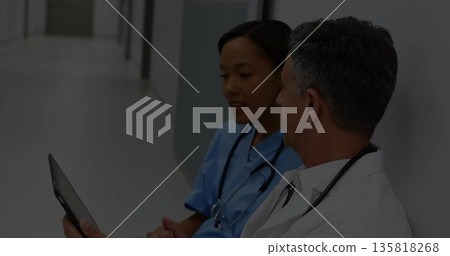 Nurse and doctor in uniforms reviewing tablet in hospital corridor with stethoscopes, copy space Nurse and doctor in uniforms reviewing tablet in hospital corridor with stethoscopes, copy space 135818268