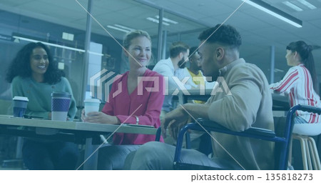 Gathering team chatting at office table near glass walls, with wheelchair user holding coffee mug Gathering team chatting at office table near glass walls, with wheelchair user holding coffee mug 135818273