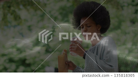 Holding white coffee cup near mouth, woman in grey blouse in park with paper bag Holding white coffee cup near mouth, woman in grey blouse in park with paper bag 135818305