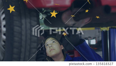 Inspecting mechanic in coveralls gloved checking car exhaust on lift in garage with yellow stars Inspecting mechanic in coveralls gloved checking car exhaust on lift in garage with yellow stars 135818327