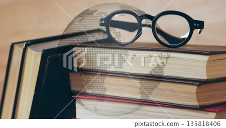 Resting black eyeglasses on hardcover book stack on desk, with digital globe overlay Resting black eyeglasses on hardcover book stack on desk, with digital globe overlay 135818406