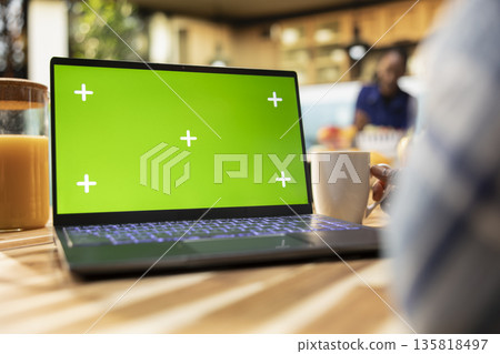 Isolated mockup laptop next to boyfriend drinking coffee over breakfast in a modern kitchen, representing domestic life and healthy lifestyle habits at home. Homey kitchen table with food. Isolated mockup laptop next to boyfriend drinking coffee over breakfast in a modern kitchen, representing domestic life and healthy lifestyle habits at home. Homey kitchen table with food. 135818497