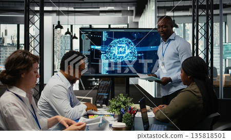 Programmer gives presentation to executives, implementing AI chatbot reducing work volume. Startup office IT expert analyzing business insights for management using artificial intelligence, camera A Programmer gives presentation to executives, implementing AI chatbot reducing work volume. Startup office IT expert analyzing business insights for management using artificial intelligence, camera A 135818501