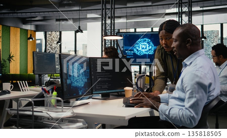 Data scientists doing brainstorming in office, using specialized hardware to accelerate complex AI calculations. IT professionals collaborating, managing deep learning datasets systems, camera A 135818505