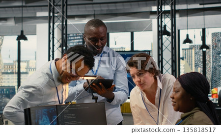 Engineering team in office using AI to optimize company systems performance. Coworkers in startup office use artificial intelligence technology to automate tasks, camera B 135818517