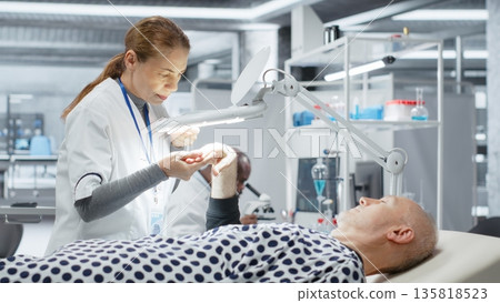 Magnifying glass used by medic monitoring a senior man for clinical trial in laboratory, checking the skin of the patient. Female expert working in lab for medical breakthrough. Camera B. 135818523