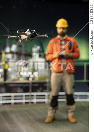Close up of drone deployed by offshore platform maintenance crew worker to assess hard to reach equipment areas. Drilling rig expert flies UAV to inspect machinery components without risking safety Close up of drone deployed by offshore platform maintenance crew worker to assess hard to reach equipment areas. Drilling rig expert flies UAV to inspect machinery components without risking safety 135818538