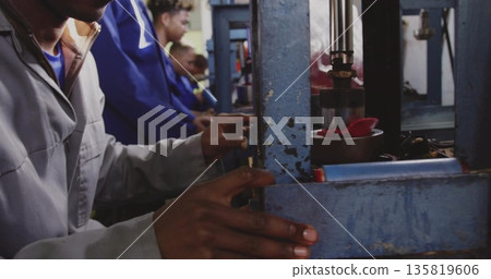Gripping lever operator in grey coveralls operating blue hydraulic press at factory, copy space Gripping lever operator in grey coveralls operating blue hydraulic press at factory, copy space 135819606