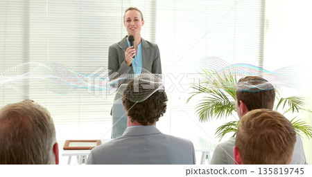 Speaking woman presenter in grey blazer at small conference room, with microphone Speaking woman presenter in grey blazer at small conference room, with microphone 135819745