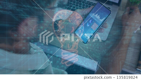 IT worker holding smartphone viewing data charts at desk, with laptop digital overlay, copy space 135819824