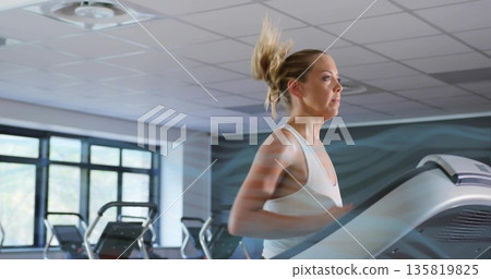 Running female wearing athletic tank top and leggings on treadmill in fitness center, with windows Running female wearing athletic tank top and leggings on treadmill in fitness center, with windows 135819825