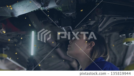 Inspecting exhaust pipe woman mechanic in coverall using LED light in service bay, copy space 135819944