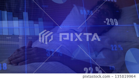 Lying mature adult patient wearing white gown on hospital bed, with translucent charts overlay 135819964