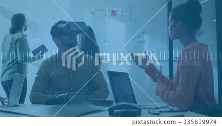 Collaborating colleagues wearing VR headset using laptop in conference room, with whiteboard notes Collaborating colleagues wearing VR headset using laptop in conference room, with whiteboard notes 135819974