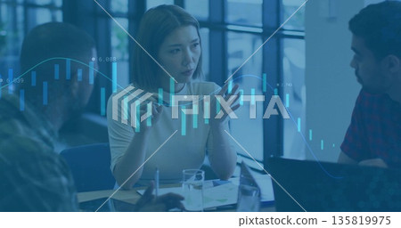 Discussing three colleagues analyzing financial trends in office with laptops, candlestick overlay 135819975