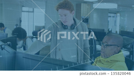 Guiding red-haired developer collaborating with hoodie engineer at open-plan office, with monitors 135820046